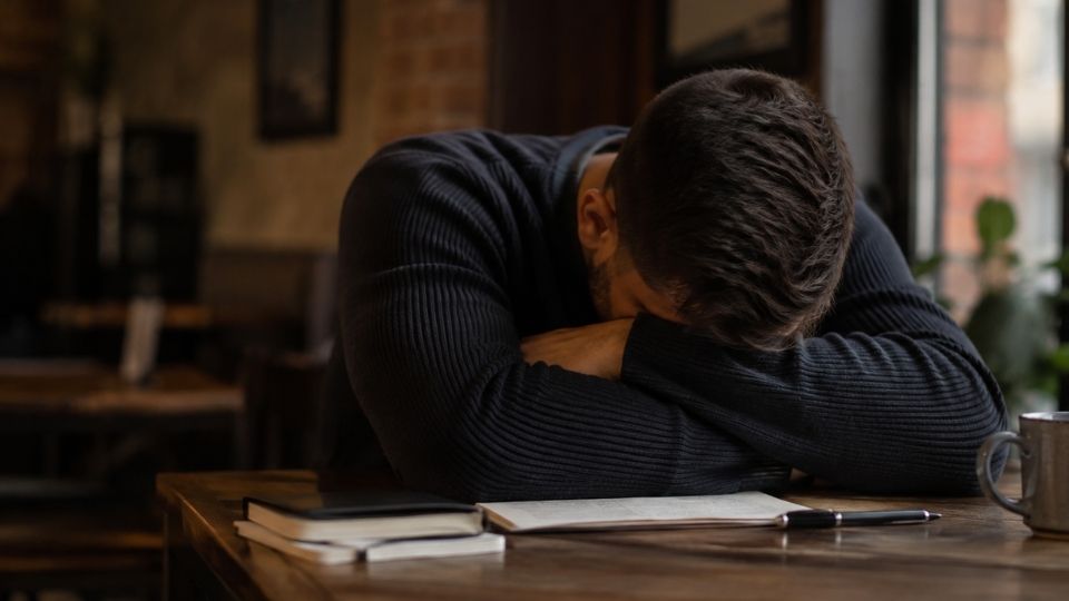 Alcohol Poisoning hero image of a man with his head down on a desk.