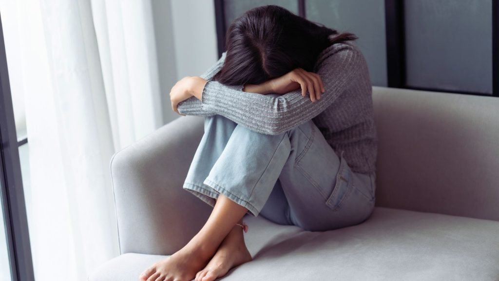 Person sitting on a couch showing emotional distress linked to benzodiazepine dependence