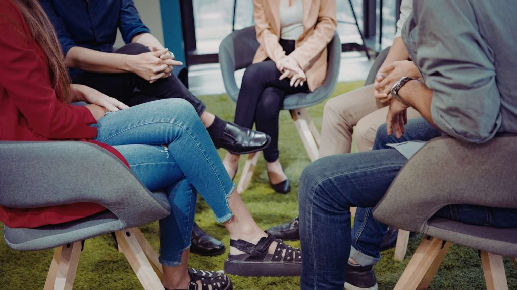 Small group seated in discussion during addiction treatment group therapy session