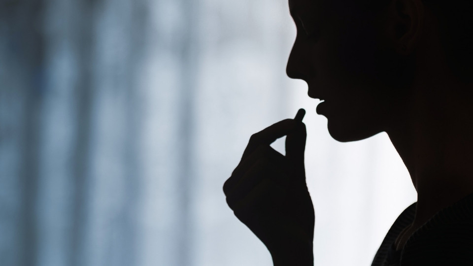 Is Xanax a Narcotic hero image of a woman in shadow taking a pill.