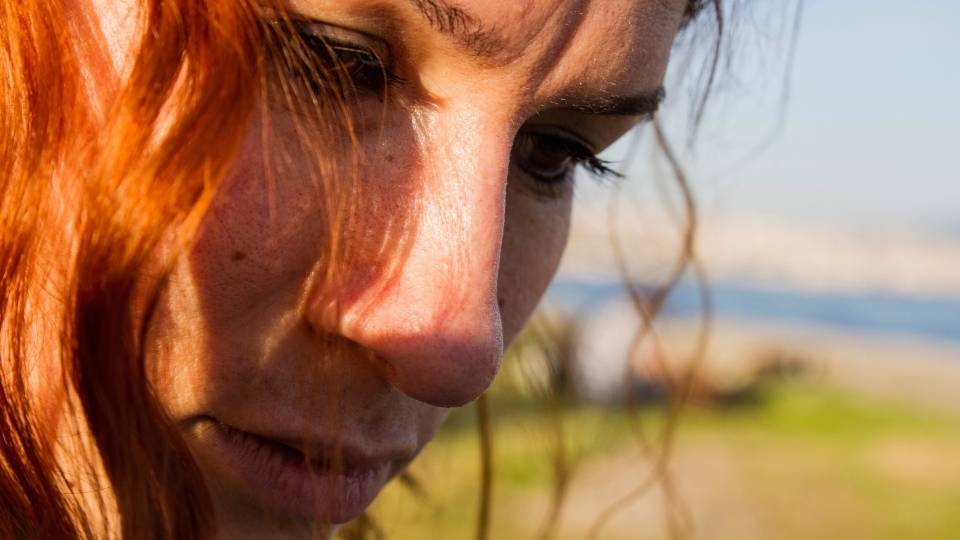 a woman looks down after thinking about meth sores and other health risks for meth.